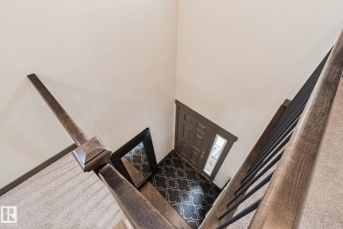 Warm wood-finish handrail with metal balusters - 1337 Secord Landing Nw, Edmonton, AB - Indoor Photo Showing Other Room