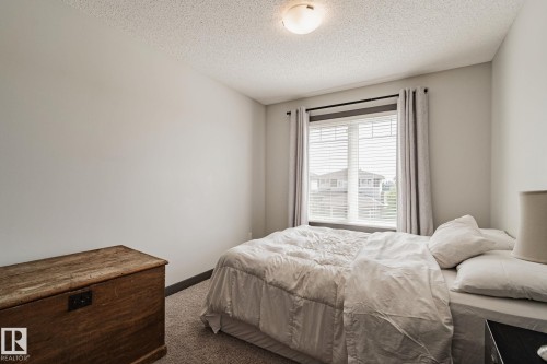 Neutral-toned walls, textured ceiling, flush-mount ceiling light, window with blinds, and carpeted flooring - 1337 Secord Landing Nw, Edmonton, AB - Indoor Photo Showing Bedroom