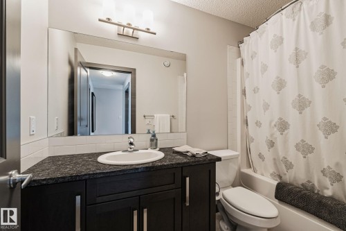Bathroom featuring a dark wood-finish vanity with an undermount sink, dark countertop, and brushed nickel hardware - 1337 Secord Landing Nw, Edmonton, AB - Indoor Photo Showing Bathroom
