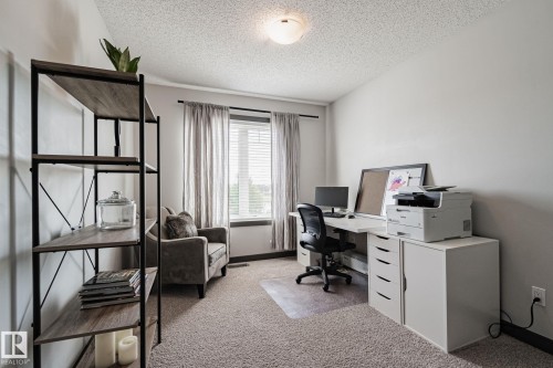 Recessed window with blinds and drapes, wall-to-wall carpeting, and a ceiling-mounted light fixture - 1337 Secord Landing Nw, Edmonton, AB - Indoor Photo Showing Office