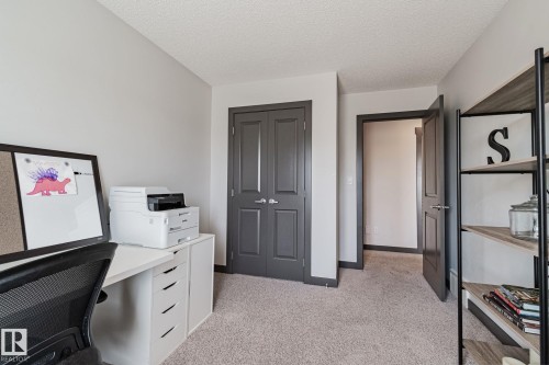 Neutral wall paint, light-toned carpeting, dark interior doors with panel detailing, and a built-in shelving unit - 1337 Secord Landing Nw, Edmonton, AB - Indoor
