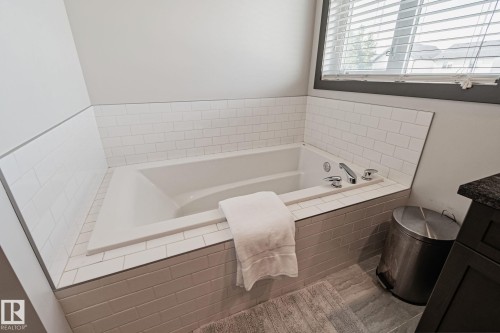Built-in soaking tub with subway tile surround, chrome fixtures, and a window with blinds - 1337 Secord Landing Nw, Edmonton, AB - Indoor Photo Showing Bathroom