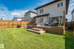 Expansive backyard featuring a manicured lawn, a wooden fence, and a multi-level wooden deck with steps - 