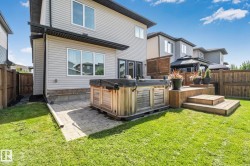 Expansive backyard featuring a wood-finish hot tub, multi-level wood-finish deck, and a manicured lawn - 