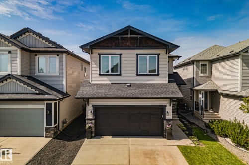 Contemporary exterior featuring light-toned siding, dark trim, and a prominent front-facing garage - 1337 Secord Landing Nw, Edmonton, AB - Outdoor With Facade
