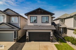 Contemporary exterior featuring light-toned siding, dark trim, and a prominent front-facing garage - 