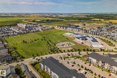Expansive neighborhood featuring residential properties, a large green space, a community building, and paved roadways - 1337 Secord Landing Nw, Edmonton, AB - Outdoor With View