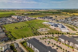 Expansive neighborhood featuring residential properties, a large green space, a community building, and paved roadways - 