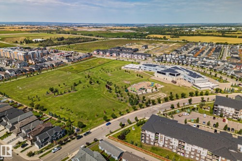 Expansive green spaces with mature trees, a playground, and a sports field - 1337 Secord Landing Nw, Edmonton, AB - Outdoor With Body Of Water With View