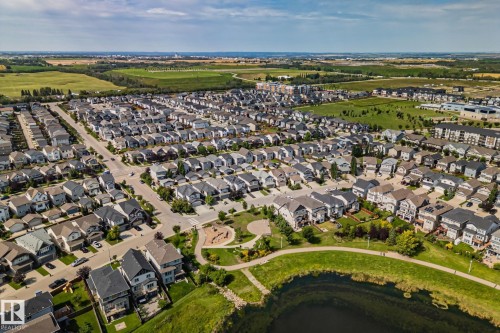 Residential development featuring a pond with surrounding green space, paved walking paths, and a playground - 1337 Secord Landing Nw, Edmonton, AB - Outdoor With View
