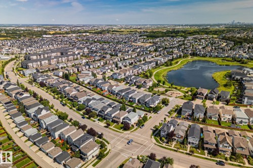 Residential community with a central pond, surrounding green spaces, and a mix of detached homes and multi-family buildings - 1337 Secord Landing Nw, Edmonton, AB - Outdoor With View