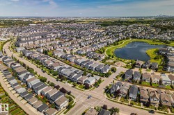Residential community with a central pond, surrounding green spaces, and a mix of detached homes and multi-family buildings - 