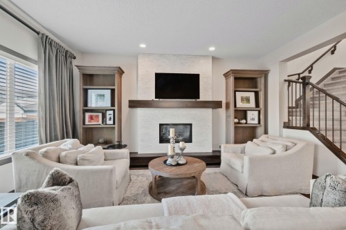 Fireplace featuring a stone facade and wood mantel - 1337 Secord Landing Nw, Edmonton, AB - Indoor Photo Showing Living Room With Fireplace
