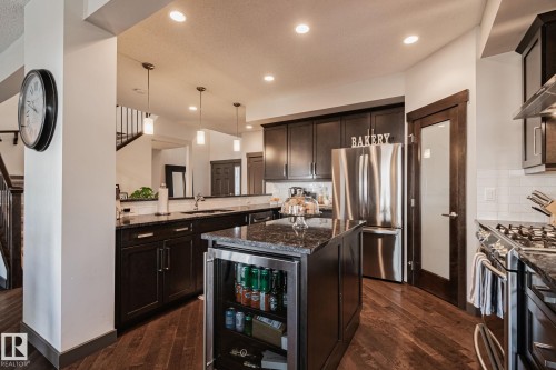 Kitchen featuring dark wood cabinetry, stainless steel appliances, recessed lighting, and wood-finish flooring - 1337 Secord Landing Nw, Edmonton, AB - Indoor Photo Showing Kitchen With Stainless Steel Kitchen With Upgraded Kitchen
