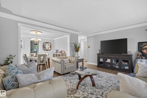 Spacious living area featuring wood-finish flooring, crown molding, and a wide cased opening to the dining area - 8632 184 Street Nw, Edmonton, AB - Indoor Photo Showing Living Room