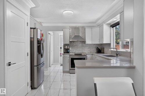 Kitchen featuring white cabinetry, stainless steel appliances, a tile backsplash, and light-toned countertops - 8632 184 Street Nw, Edmonton, AB - Indoor Photo Showing Kitchen With Stainless Steel Kitchen