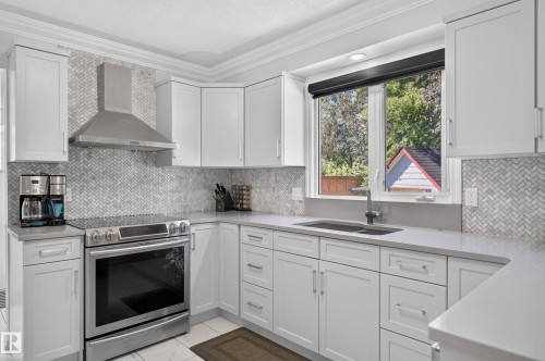 White shaker cabinetry, herringbone tile backsplash, stainless steel appliances, undermount sink with gooseneck faucet, and light-toned countertops - 8632 184 Street Nw, Edmonton, AB - Indoor Photo Showing Kitchen With Double Sink With Upgraded Kitchen