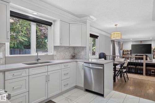 White shaker cabinetry, stainless steel dishwasher, undermount sink, light-toned countertop, and herringbone tile backsplash - 8632 184 Street Nw, Edmonton, AB - Indoor Photo Showing Kitchen With Double Sink