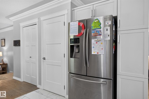 White panel doors, crown molding, light gray cabinetry, stainless steel refrigerator, and wood-finish flooring - 8632 184 Street Nw, Edmonton, AB - Indoor