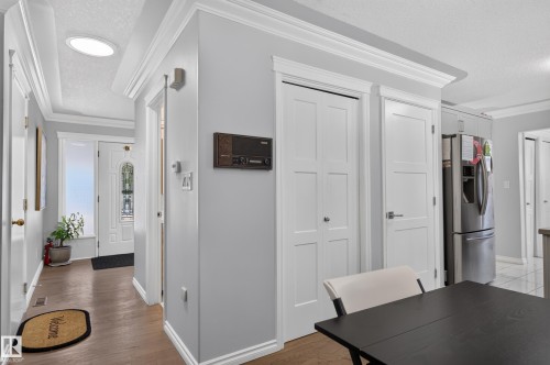 Wood-finish flooring, recessed ceiling with a circular skylight, white paneled interior doors, and a stainless steel refrigerator - 8632 184 Street Nw, Edmonton, AB - Indoor