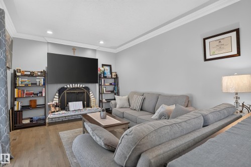 Recessed lighting, crown molding, wood-finish flooring, and a fireplace with a brick hearth - 8632 184 Street Nw, Edmonton, AB - Indoor Photo Showing Other Room