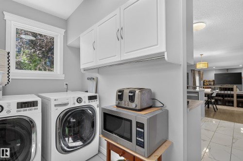 White front-loading laundry appliances, white upper cabinetry, and a single window with white trim - 8632 184 Street Nw, Edmonton, AB - Indoor Photo Showing Laundry Room