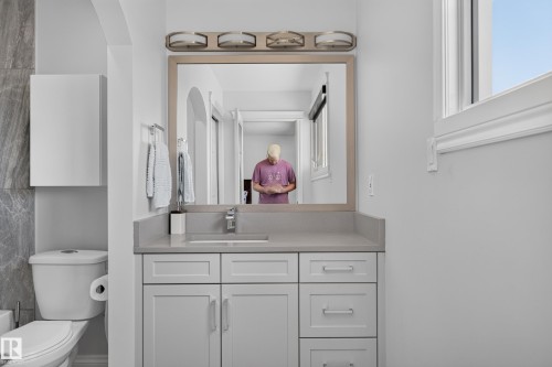 Bathroom featuring a light gray vanity with an integrated sink, a framed mirror, and a three-light vanity fixture - 8632 184 Street Nw, Edmonton, AB - Indoor Photo Showing Bathroom