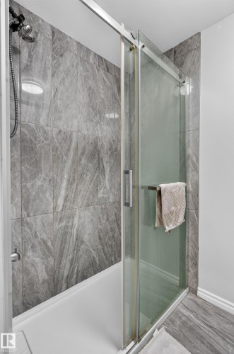 Shower enclosure with gray tile surround, sliding glass door, and a multi-function shower head - 8632 184 Street Nw, Edmonton, AB - Indoor Photo Showing Bathroom