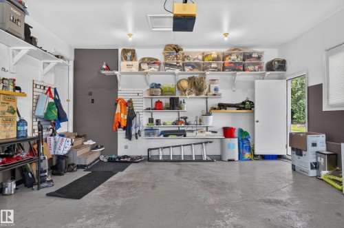 Garage featuring concrete flooring, built-in shelving, two overhead lights, a side window, and an exterior access door - 8632 184 Street Nw, Edmonton, AB - Indoor Photo Showing Garage