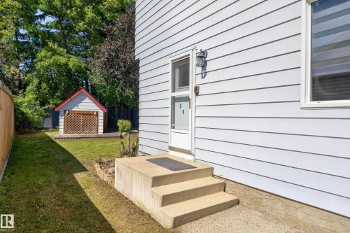 White siding exterior with a concrete stair entry, private fenced yard, and a shed with a red roof - 8632 184 Street Nw, Edmonton, AB - Outdoor With Exterior