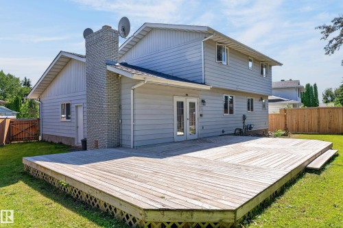 Expansive wood deck with lattice skirting, double French doors, light gray siding, and a brick chimney - 8632 184 Street Nw, Edmonton, AB - Outdoor With Exterior