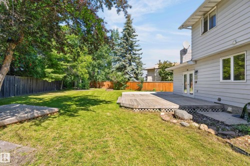 Expansive backyard featuring a large wooden deck, dual French doors, and mature perimeter trees - 8632 184 Street Nw, Edmonton, AB - Outdoor