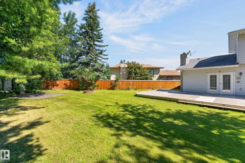 Expansive backyard featuring a meticulously manicured lawn, mature shade trees, and wooden privacy fencing - 8632 184 Street Nw, Edmonton, AB - Outdoor