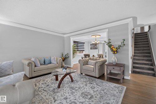 Hardwood-style flooring throughout, crown molding detailing, and a carpeted staircase - 8632 184 Street Nw, Edmonton, AB - Indoor Photo Showing Living Room