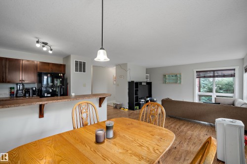 Kitchen featuring dark wood cabinetry, a breakfast bar, and black appliances - 203 Graybriar Green, Stony Plain, AB - Indoor