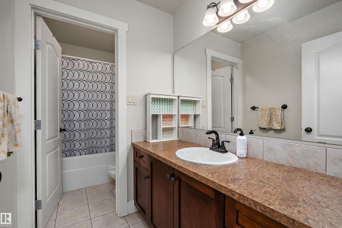 Vanity with built-in cabinetry, integrated sink, and an expansive mirror - 203 Graybriar Green, Stony Plain, AB - Indoor Photo Showing Bathroom