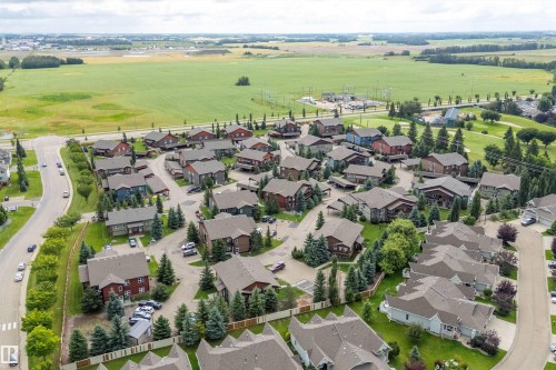 Residential community with diverse architectural styles, mature landscaping, and paved roadways, bordering expansive green fields - 203 Graybriar Green, Stony Plain, AB - Outdoor With View