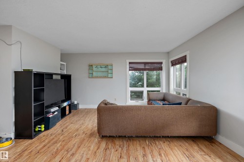 Wood-finish flooring throughout, light gray wall finishes, and white window trim - 203 Graybriar Green, Stony Plain, AB - Indoor Photo Showing Living Room