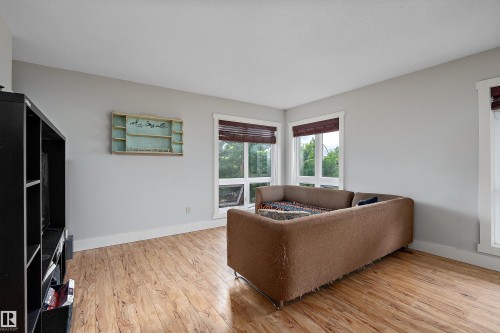 Light-toned walls, wood-finish flooring, corner windows with white trim, and dark window treatments - 203 Graybriar Green, Stony Plain, AB - Indoor Photo Showing Living Room