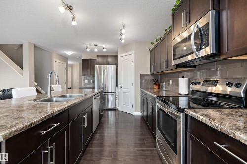 Kitchen featuring dark wood-finish cabinetry, stainless steel appliances, dark wood-finish flooring, and track lighting - 3922 Agar Court Sw, Edmonton, AB - Indoor Photo Showing Kitchen With Double Sink With Upgraded Kitchen