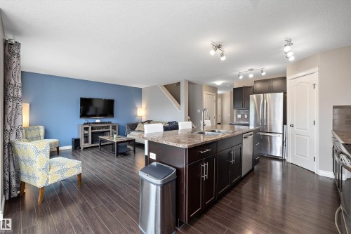 Kitchen island with dual sinks, dark wood-finish cabinetry, and stainless steel appliances - 3922 Agar Court Sw, Edmonton, AB - Indoor Photo Showing Kitchen With Double Sink With Upgraded Kitchen