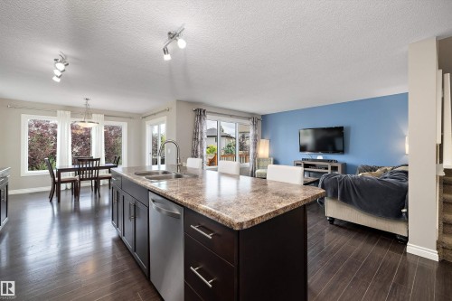 Kitchen island with an undermount double-basin sink, stainless steel dishwasher, and stone-finish countertop - 3922 Agar Court Sw, Edmonton, AB - Indoor