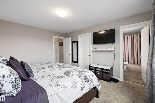 Neutral wall paint, carpet flooring, ceiling-mounted light fixture, white interior doors, and a tiled bathroom floor - 3922 Agar Court Sw, Edmonton, AB - Indoor Photo Showing Bedroom
