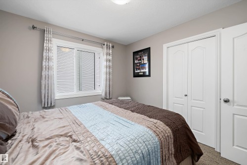 White framed window with horizontal blinds, neutral wall paint, white bi-fold closet doors, and white interior door - 3922 Agar Court Sw, Edmonton, AB - Indoor Photo Showing Bedroom