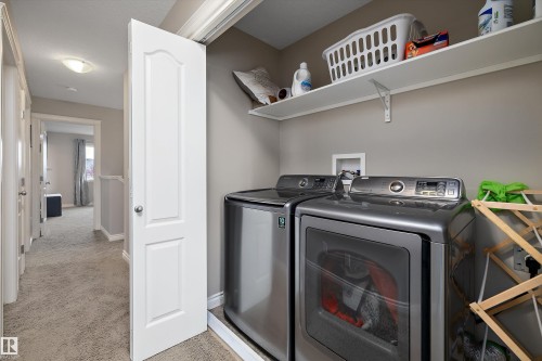 Dedicated laundry area with stacked appliances and open shelving - 3922 Agar Court Sw, Edmonton, AB - Indoor Photo Showing Laundry Room
