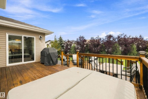 Multi-level wood deck featuring a hot tub, wood railing with black spindles, and a sliding glass door - 3922 Agar Court Sw, Edmonton, AB - Outdoor With Deck Patio Veranda With Exterior