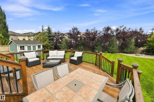 Expansive wooden deck with a built-in storage shed, complete with a manicured lawn and mature trees - 3922 Agar Court Sw, Edmonton, AB - Outdoor With Deck Patio Veranda With Exterior