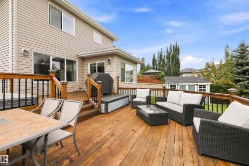 Expansive outdoor deck with wood-finish flooring, black balusters, and a built-in outdoor storage bench - 3922 Agar Court Sw, Edmonton, AB - Outdoor With Deck Patio Veranda With Exterior