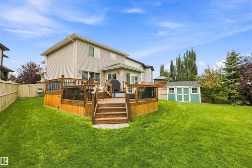 Expansive backyard featuring a multi-level wood-finish deck with railings, a manicured lawn, and a storage shed - 3922 Agar Court Sw, Edmonton, AB - Outdoor With Deck Patio Veranda With Backyard