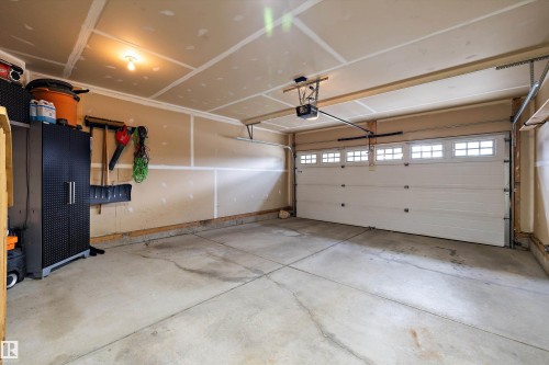 Garage space with a white sectional overhead door featuring window inserts and an automatic opener - 3922 Agar Court Sw, Edmonton, AB - Indoor Photo Showing Garage